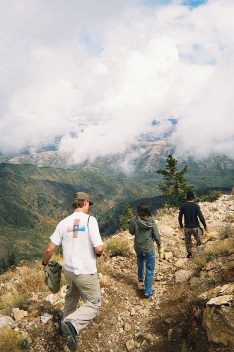 Three friends hiking down a rocky trail above the clouds