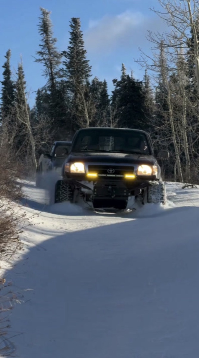 Finn's Tacoma plowing through snow on a forest road