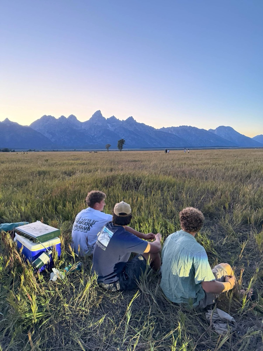 Friends sitting in a meadow below the Tetons